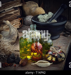 Bouteilles d'huile essentielle ou de potion, mortier de mousse séchée, de vieux livres, des racines et des plantes sèches. La médecine de fines herbes. Banque D'Images