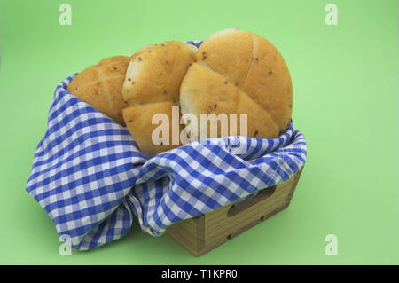 Quelques viennoiseries dans une caisse en bois et un chiffon de blanc et carré bleu sur fond vert. Banque D'Images