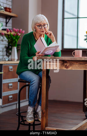 Vieillissement de la femme d'être absorbé dans un livre assis à équipée Banque D'Images