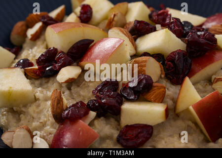 Repas d'avoine bouillie de grains entiers dans un bol alimentaire avec Apple, les canneberges et les amandes. Extreme close up. Banque D'Images