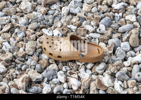 Un abandonné ou perdu ou beige marron chaussures en plastique Croc sur une plage de galets, Dorset, UK Banque D'Images