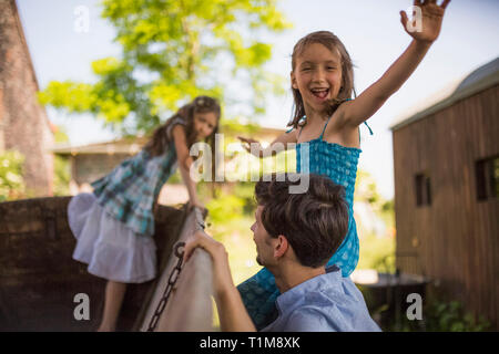 Portrait d'une fille ludique avec son père et sa sœur en chariot dans la cour Banque D'Images