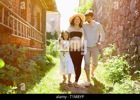 Famille enceinte marchant le long de la ferme ensoleillée Banque D'Images