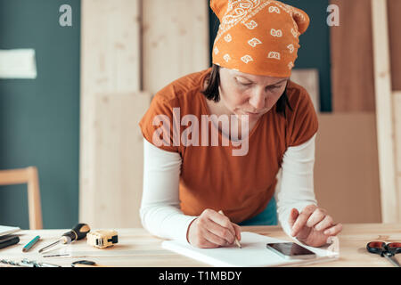 Female carpenter avec foulard tête faisant calcul financier dans l'atelier de menuiserie menuiserie Banque D'Images