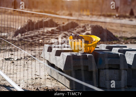 Casque de protection jaune sur le site de construction en midi Pause pendant le lancement. Les travailleurs de la construction de flou artistique méconnaissable visible en arrière-plan. Banque D'Images