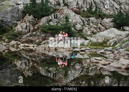 Portrait couple hiking, reposant à Rocky Mountain Lake, chien, BC, Canada Banque D'Images