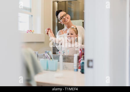 Smiling mother and daughter en miroir de salle de bains Banque D'Images