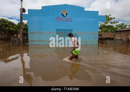 2015 Inondations en Amazonie brésilienne, jeune homme passe devant pentecostal church building Assembleia de Deus (Assemblée de Dieu) avec les mots 'Cristo é a Resposta' qui signifie 'le Christ est la réponse", à Taquari, district de la ville de Rio Branco, l'état d'Acre. Les inondations ont touché des milliers de personnes dans l'Etat d'Acre, dans le nord du Brésil, depuis le 23 février 2015, lorsque certaines des rivières de l'état, en particulier l'Acre, la rivière a débordé. De plus fortes précipitations a forcé les niveaux de la rivière plus haut encore, et le 03 mars 2015, le gouvernement fédéral du Brésil a déclaré l'état d'urgence dans l'état d'Acre, où cu Banque D'Images