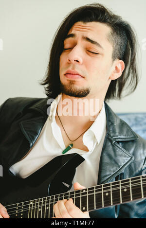 Jeune guitariste d'Amérique latine avec l'expression de concentration lors de la lecture d'un morceau de rock. Banque D'Images