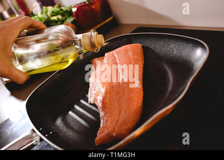 Filet de saumon cru dans la poêle, faire cuire l'huile d'olive verser dessus pour la faire cuire. Banque D'Images