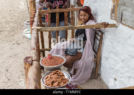 Andavadoaka, Madagascar - Janvier 13th, 2019 : Malagasy femme vendant des fruits secs placés sur des tables en bois à Andavadoaka, Madagascar. Banque D'Images