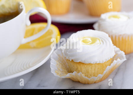 Libre d'un cupcake au citron avec glaçage blanc et d'une tasse de thé avec petits gâteaux sur un blurredbackground Banque D'Images