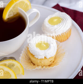 Gros plan du lemon cupcakes avec glaçage blanc et une tasse de thé sur une plaque Banque D'Images