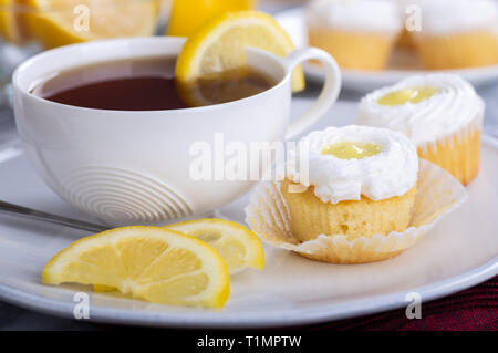 Libre d'un cupcake au citron avec glaçage blanc et une tasse de thé sur une plaque Banque D'Images