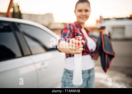 Femme avec spray à la main, lavage de voiture en libre-service Banque D'Images