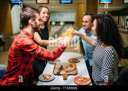 Les Amis des boissons et mange de la pizza au bowling club Banque D'Images