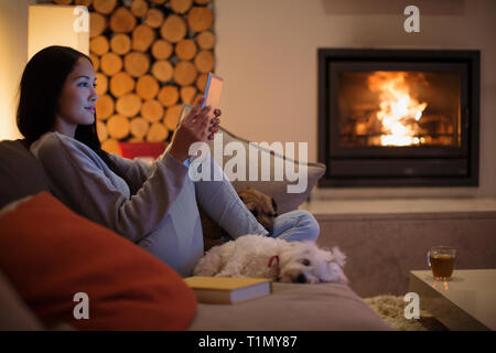 Jeune femme avec des chiens à l'aide de tablette numérique sur salon canapé Banque D'Images