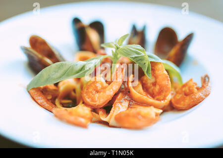 Les pâtes en sauce tomate et fruits de mer servis pièces sur une large plaque blanche Banque D'Images