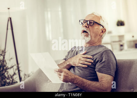 Choqué homme avoir une attaque cardiaque après lecture de documents Banque D'Images