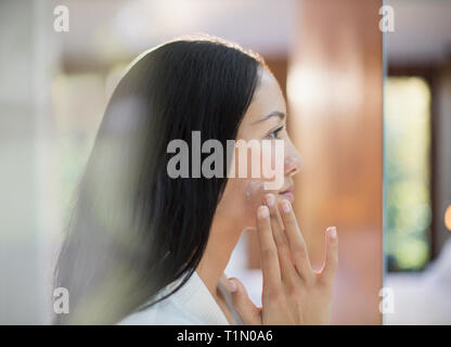Jeune Femme de profil d'appliquer l'hydratant sur les joues Banque D'Images