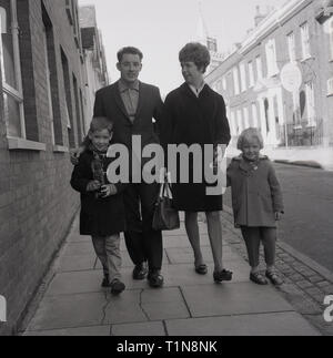 1967, marcher le long d'un trottoir dans une rue urbaine, England, UK. Banque D'Images