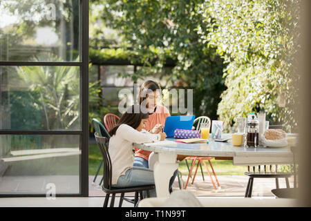 Mère et fille à l'aide d'ordinateur portable et faire ses devoirs à la table Banque D'Images