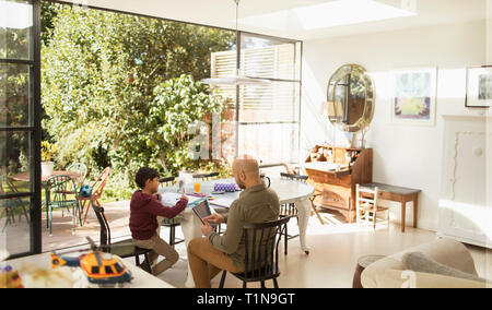 Père et fils à l'aide de tablette numérique et la coloration à table à manger Banque D'Images