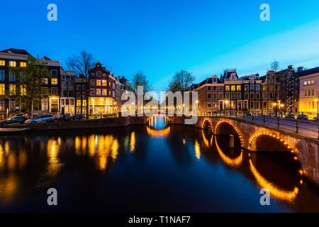 Vue sur la ville d'Amsterdam, aux Pays-Bas avec la rivière Amstel la nuit. Banque D'Images