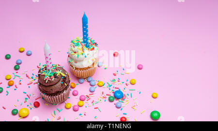 Garçon et fille d'anniversaire. Deux cupcakes vanille et chocolat avec des bougies sur rose pastel arrière-plan, copiez l'espace. Banque D'Images