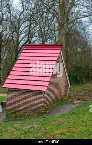 Petite maison en pierre avec une pente de toit rouge au milieu d'une forêt Banque D'Images