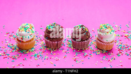 Cupcakes sur fond rose vif. Quatre cupcakes vanille et chocolat avec des Sprinkles, vue rapprochée Banque D'Images