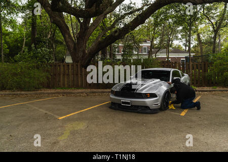 Le nettoyage d'un homme américain argent muscle car sous des chênes. Banque D'Images