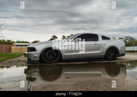 Silver American muscle car reflète dans l'eau sous un ciel nuageux. Banque D'Images