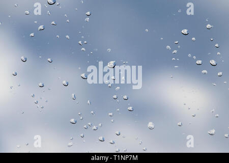 Vue sur le ciel à travers la vitre avec gouttes de pluie bleu sur fond flou. - Image Banque D'Images