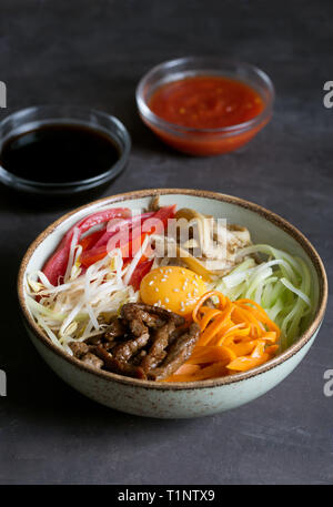 Plat de riz coréen bibimbap. Généralement servi comme un bol de riz blanc chaud avec des légumes et des oeufs. Fond noir Banque D'Images