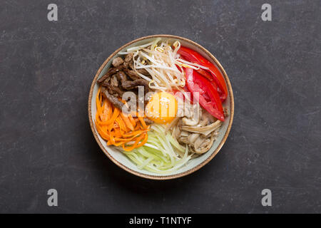 Plat de riz coréen bibimbap. Généralement servi comme un bol de riz blanc chaud avec des légumes et des oeufs. Fond noir, vue du dessus Banque D'Images