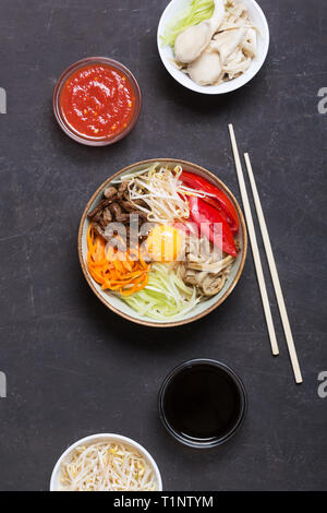 Plat de riz coréen bibimbap. Généralement servi comme un bol de riz blanc chaud avec des légumes et des oeufs. Fond noir, vue du dessus Banque D'Images