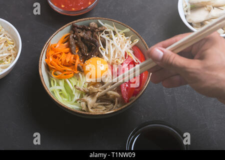 Plat de riz coréen bibimbap. Généralement servi comme un bol de riz blanc chaud avec des légumes et des oeufs. Fond noir Banque D'Images