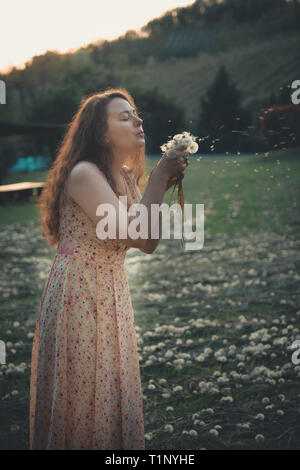 Happy woman blowing dandelion dans le domaine Banque D'Images