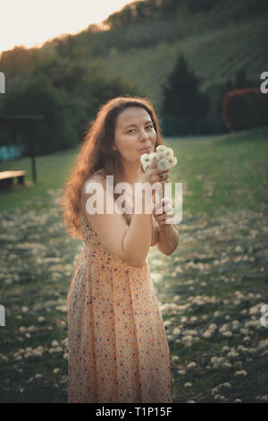 Pretty girl blowing dandelion dans parc d'été. La belle nature de l'herbe verte Banque D'Images