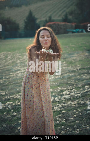 Pretty girl blowing dandelion dans parc d'été. La belle nature de l'herbe verte Banque D'Images