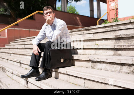 Portrait d'un homme d'affaires s'ennuyer assis sur des escaliers. Banque D'Images