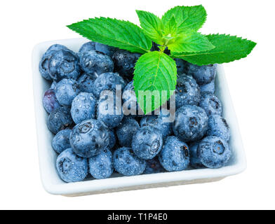 Les bleuets humide pile. Les feuilles de menthe. Gouttes d'eau. Bol carré. Isolé sur fond blanc. Les myrtilles fraîches. Menthe verte décorative. Blue berry. Banque D'Images