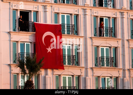 Izmir, Turquie - le 29 octobre 2018 : drapeau turc accroché sur un bâtiment avec deux personne à Alsancak Izmir Turquie. Banque D'Images