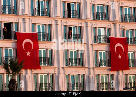 Izmir, Turquie - le 29 octobre 2018 : drapeaux turcs accroché sur un bâtiment avec deux personne à Alsancak Izmir Turquie. Banque D'Images