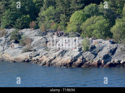 13 juillet 2018, la Suède, Stockholm : les touristes se tiennent sur une île rocheuse près de la capitale suédoise. Stockholm comprend 14 îles d'un grand archipel dans la mer Baltique, reliés par plus de 50 ponts. Photo : Holger Hollemann/dpa Banque D'Images