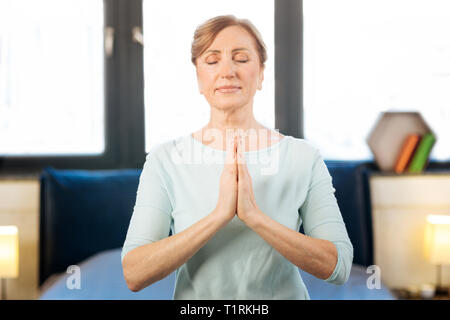 Femme adulte pacifique dans l'état méditatif tout en ayant des séance de yoga Banque D'Images