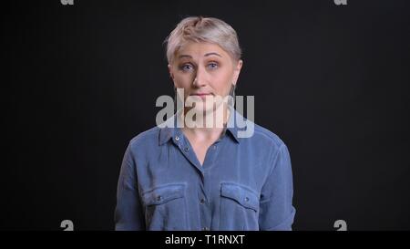 Closeup portrait of attractive young adultes femme avec de courts cheveux blonds d'être surpris et d'avoir ses yeux grand ouvert à la recherche à l'appareil photo avec Banque D'Images