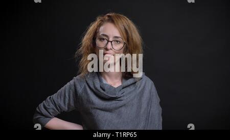 Closeup portrait of middle-aged femme rousse extravagante dans les verres en colère et furieux et avoir la main sur une hanche en avant de l'appareil photo Banque D'Images