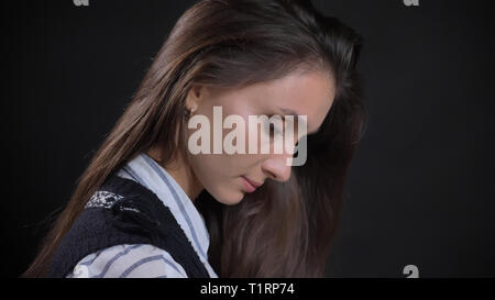 Vue côté gros plan portrait de jeune femme de race blanche avec la face vers le bas à la recherche de cheveux brune avec fond isolé Banque D'Images